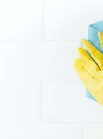 Hand and glove cleaning the bathroom tiles.